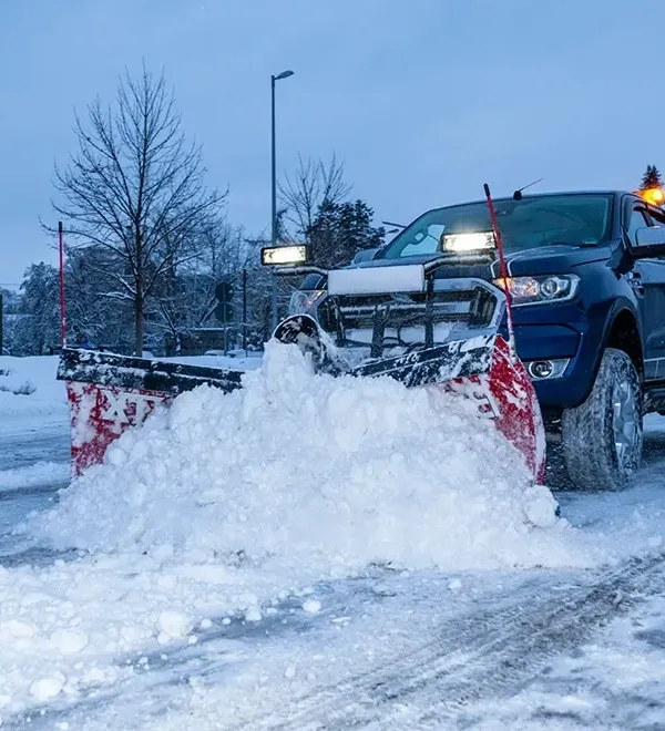 Pickup mit Räumschild schiebt Schnee auf einer Verkehrsfläche